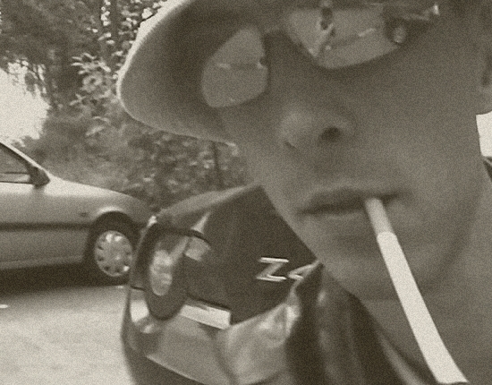 junger Mann mit albernem blauen Strickhut, Sonnenbrille, Zigarette